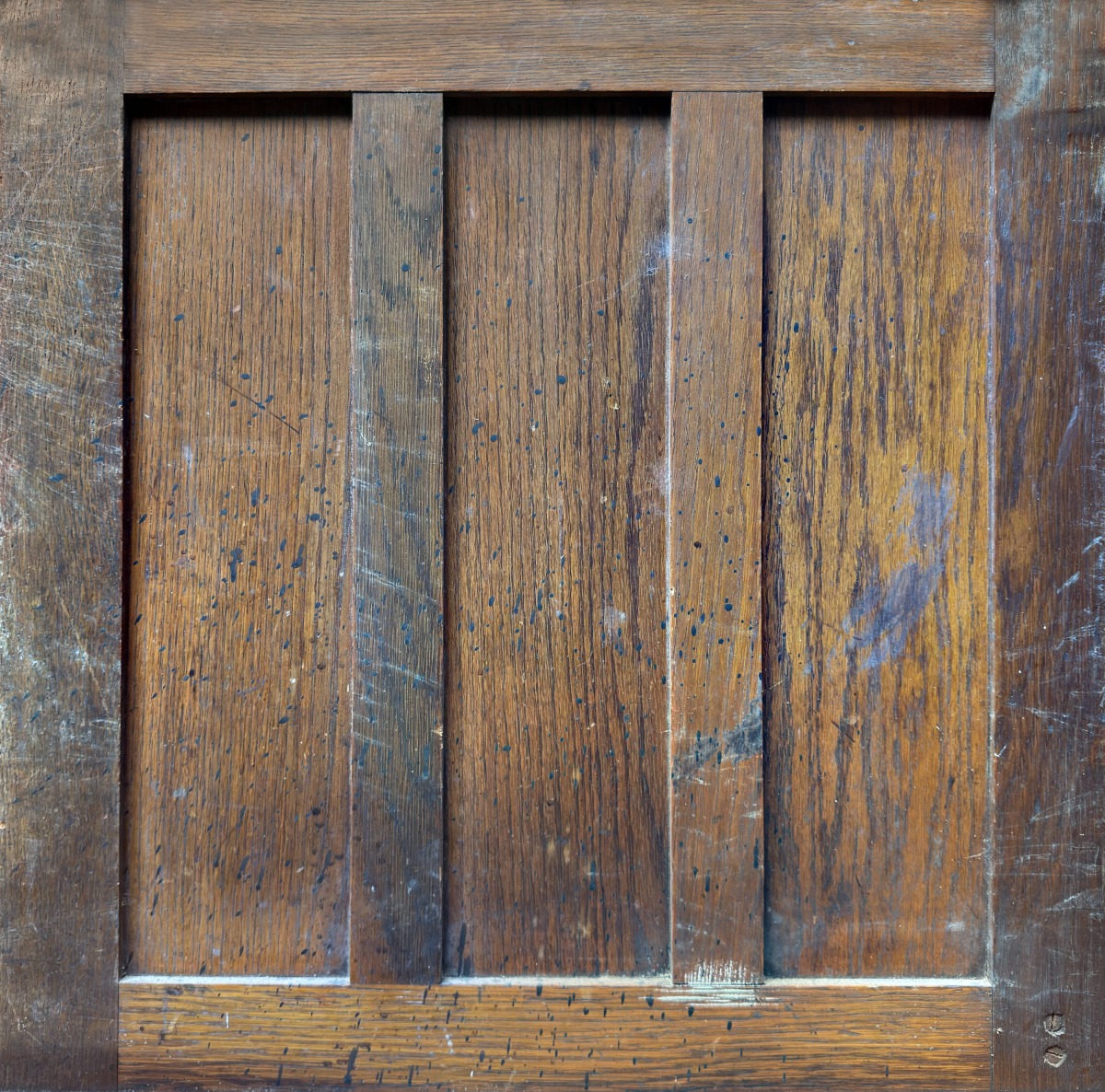A wooden cupboard door with visible grain, aged finish, and paint splatters, used for furniture or interior decor.