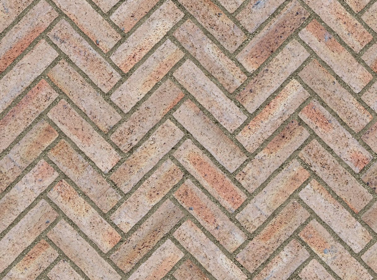 Beige and light brown clay brick paving arranged in a herringbone pattern with mortar joints